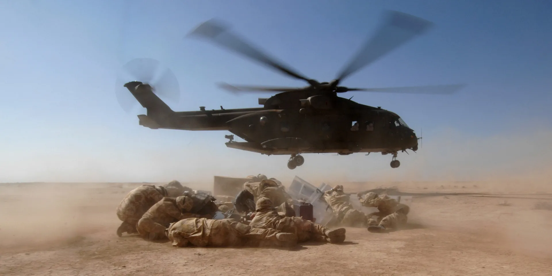 Members of a Queen's Royal Lancers patrol take cover from the dust in a Merlin helicopter's downdraught, Iraq, 2007