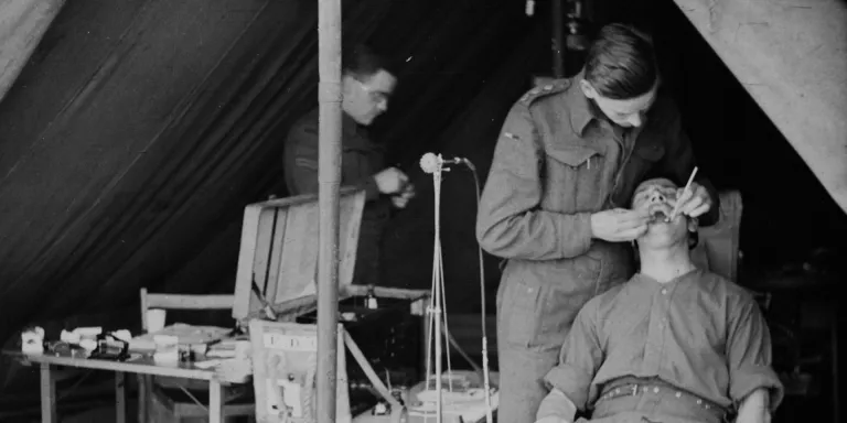 Captain Rushby practising dentistry on a patient in the front line, February 1943