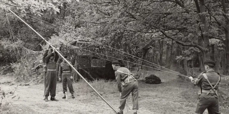 Royal Corps of Signals soldiers erect a radio aerial, c1955