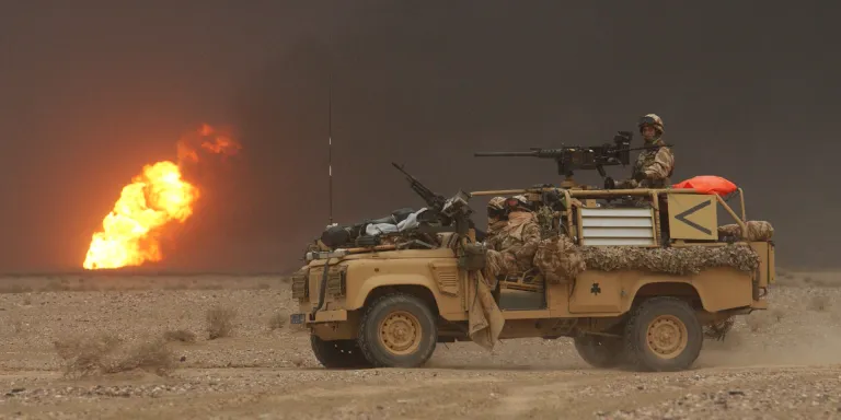 A Royal Irish Regiment vehicle passes a burning oil well during the invasion of Iraq, March 2003
