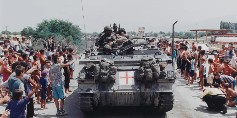 A British Warrior tracked vehicle passing Stenkovich refugee camp on the Macedonia-Kosovo border, 1999