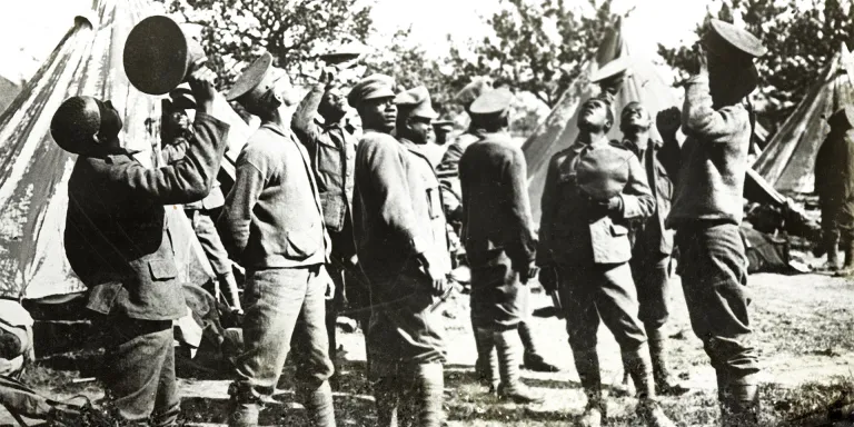 Soldiers of the British West Indies Regiment observe aircraft above their camp on the Albert to Amiens road, France, 1918