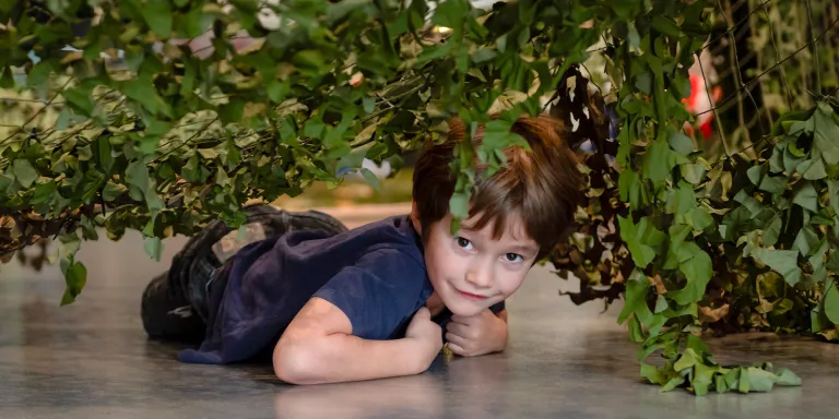 Child crawling underneath a camouflage net